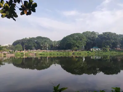 Still water of DC Lake reflecting the surrounding trees, Tangail town